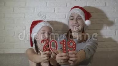 两个姐姐，一个小女孩和一个十几岁的孩子，戴着圣诞老人`帽子，戴着红色的数字，玩着，坐在上面微笑